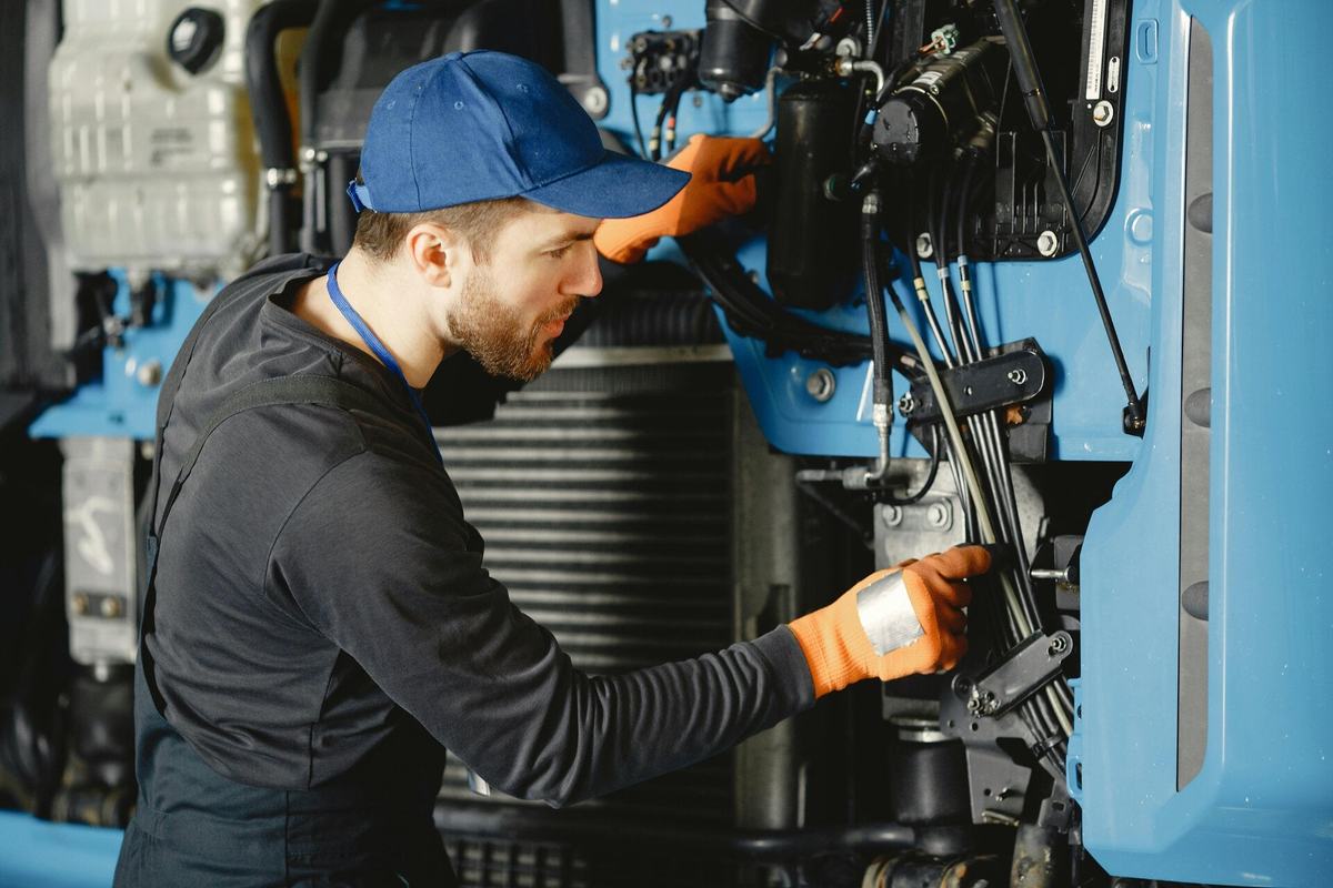 Technician reaching into the engine compartment of a blue cab-over truck